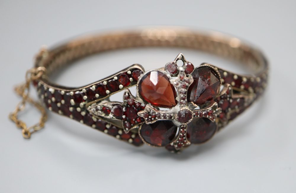 A Victorian gilt white metal and garnet set hinged bangle.